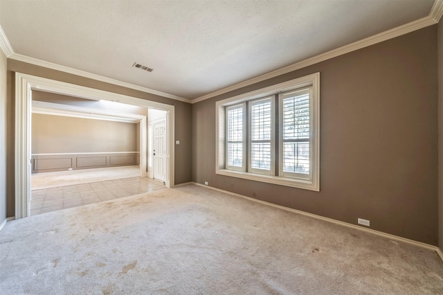 interior space featuring visible vents, baseboards, ornamental molding, and carpet flooring