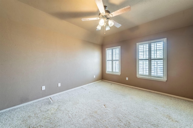 empty room featuring carpet flooring, ceiling fan, baseboards, and vaulted ceiling