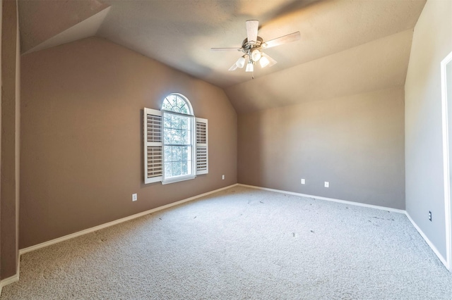 carpeted empty room with lofted ceiling, baseboards, and ceiling fan