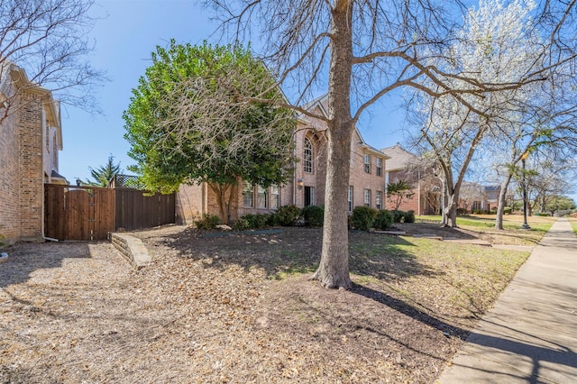 view of side of property featuring brick siding, a gate, and fence