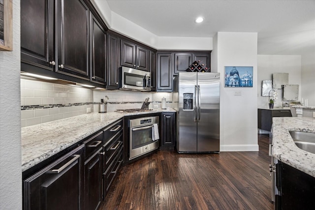 7917 Parkwood Blvd, Plano, TX 75024 - kitchen with appliances with stainless steel finishes, dark wood-style floors, light stone counters, tasteful backsplash, and recessed lighting