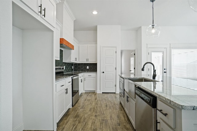 kitchen with a kitchen island with sink, decorative backsplash, dark wood-type flooring, appliances with stainless steel finishes, and white cabinetry