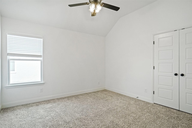 empty room featuring baseboards, carpet floors, lofted ceiling, and a ceiling fan