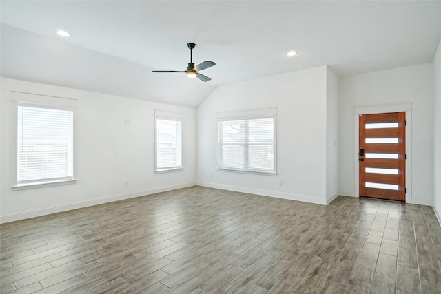 interior space with vaulted ceiling, wood finished floors, baseboards, and ceiling fan