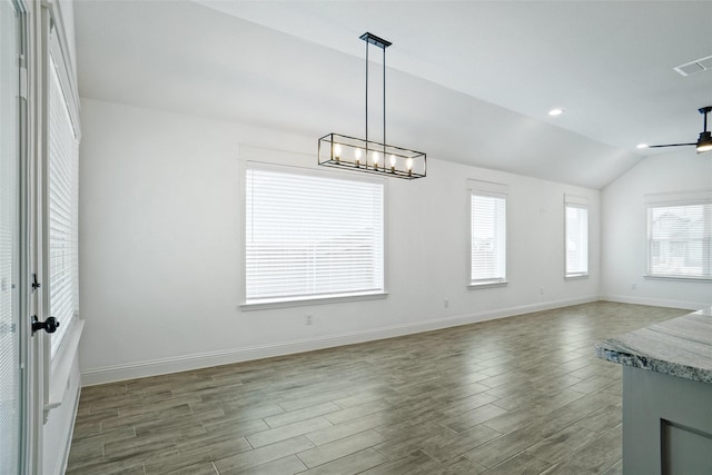 unfurnished dining area with visible vents, ceiling fan, baseboards, lofted ceiling, and wood finished floors