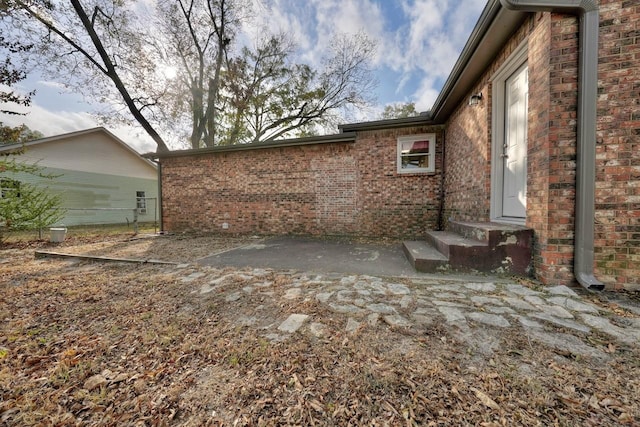 view of property exterior featuring a patio area and brick siding