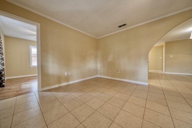 unfurnished room with light tile patterned floors, baseboards, visible vents, arched walkways, and ornamental molding