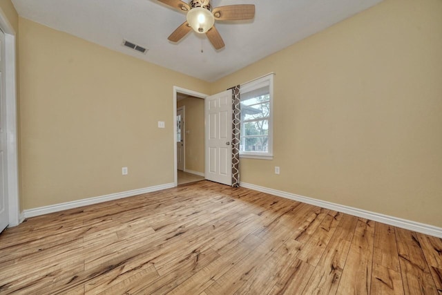 spare room with light wood-type flooring, visible vents, baseboards, and ceiling fan