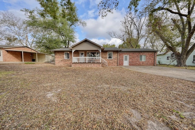 ranch-style home with brick siding, covered porch, and driveway