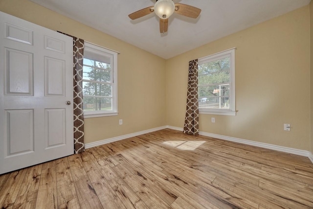 spare room featuring light wood finished floors, plenty of natural light, and baseboards