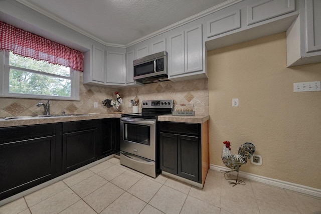 kitchen with tasteful backsplash, baseboards, light countertops, stainless steel appliances, and a sink