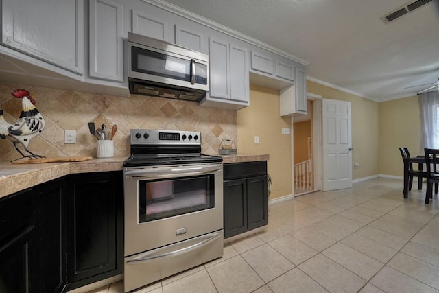 kitchen with visible vents, backsplash, light countertops, light tile patterned floors, and appliances with stainless steel finishes