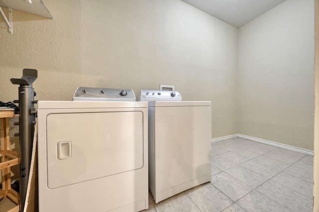 laundry room with laundry area, light tile patterned flooring, baseboards, and washing machine and clothes dryer