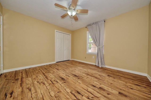 unfurnished bedroom with a closet, baseboards, wood finished floors, and a ceiling fan