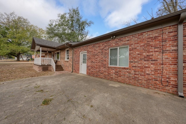 view of side of home featuring a patio, brick siding, and driveway