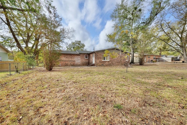 exterior space featuring a front yard, fence, and brick siding