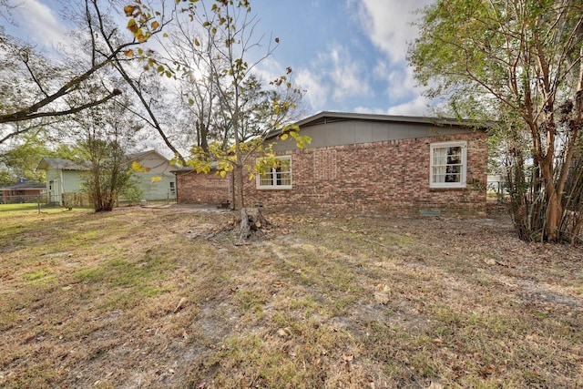 view of home's exterior featuring brick siding and a yard