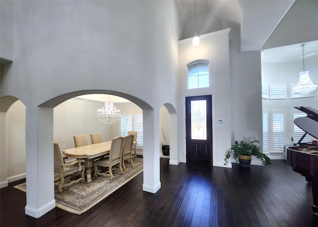 entrance foyer with a high ceiling, wood finished floors, baseboards, and arched walkways