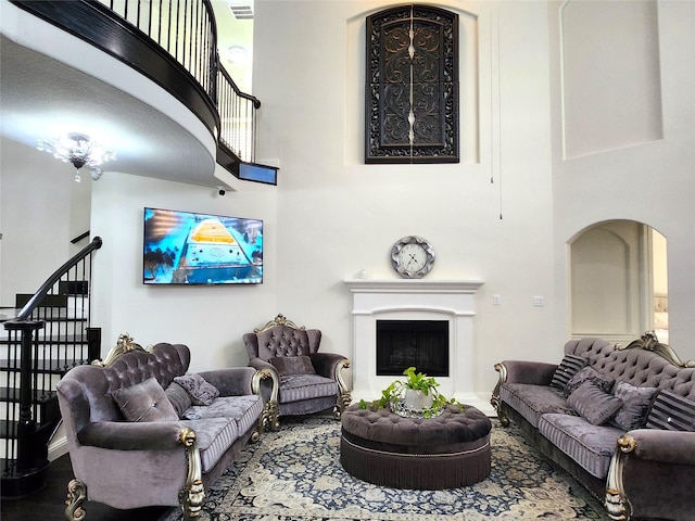 living room with stairs, visible vents, a high ceiling, and a fireplace