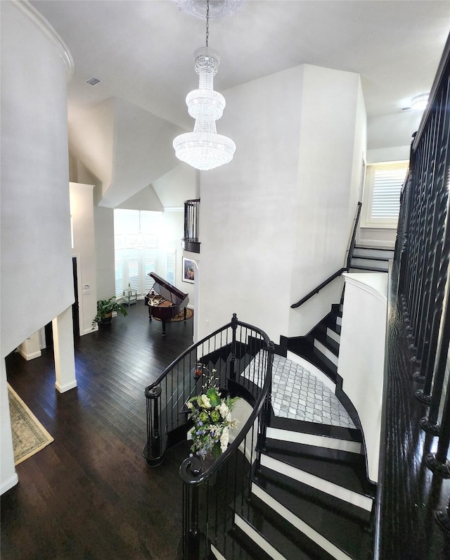 stairway with visible vents, a notable chandelier, and wood finished floors