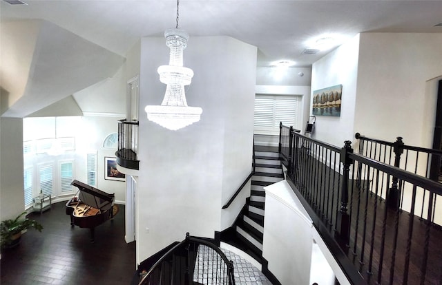 hall featuring an upstairs landing, a notable chandelier, and wood finished floors