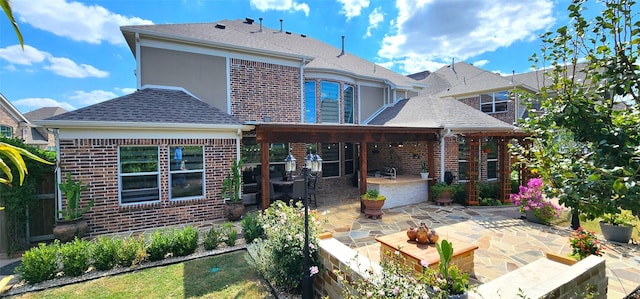 back of property featuring a patio area, brick siding, and roof with shingles