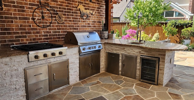 view of patio featuring fence, exterior kitchen, area for grilling, a sink, and wine cooler