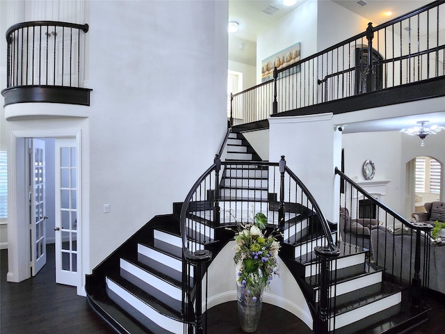 stairs featuring a high ceiling, wood finished floors, visible vents, and baseboards