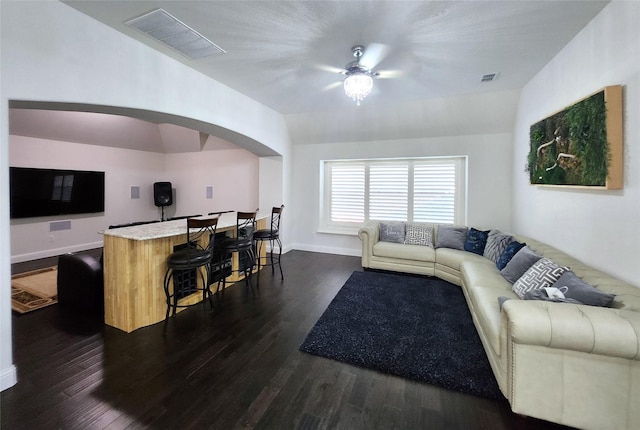 living room featuring dark wood-style floors, visible vents, arched walkways, and baseboards