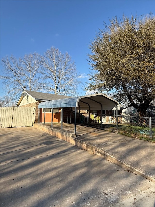 view of vehicle parking with a carport, driveway, and fence