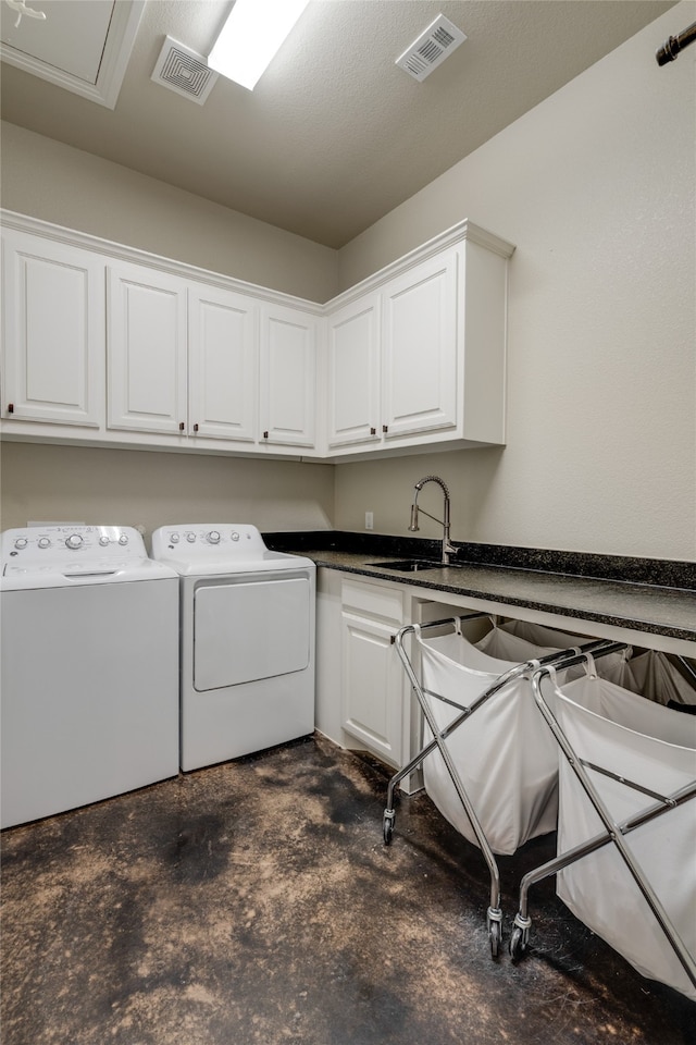 washroom with a sink, visible vents, cabinet space, and washing machine and dryer