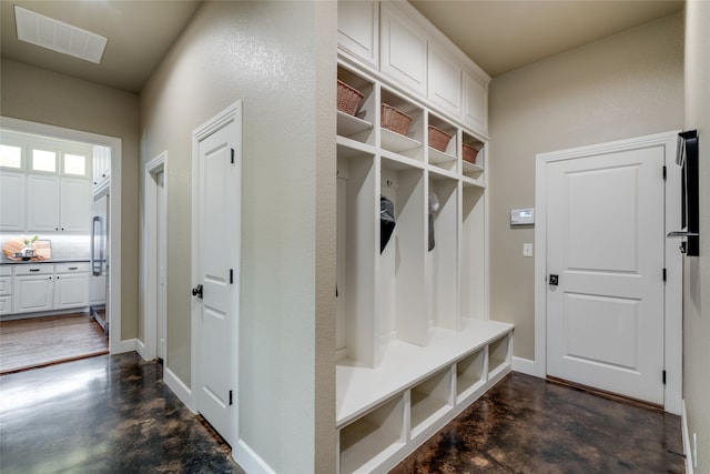 mudroom featuring finished concrete flooring, visible vents, and baseboards