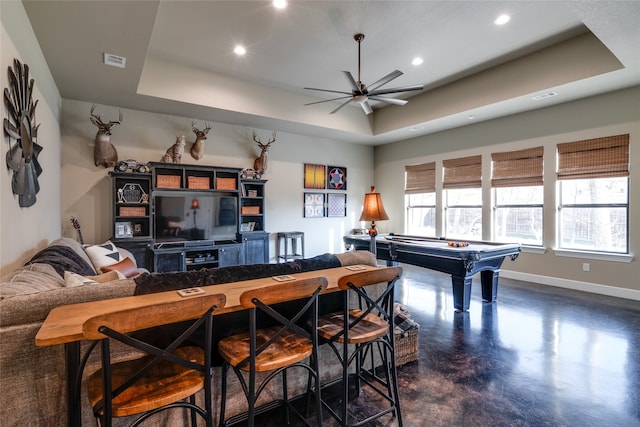 recreation room with visible vents, baseboards, concrete flooring, and a tray ceiling