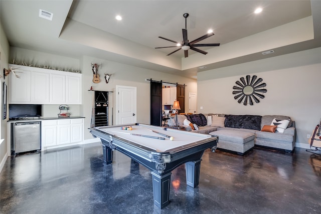 recreation room featuring baseboards, visible vents, finished concrete floors, a barn door, and a raised ceiling