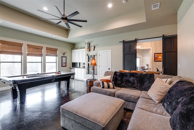 game room with a ceiling fan, visible vents, concrete floors, a barn door, and a raised ceiling