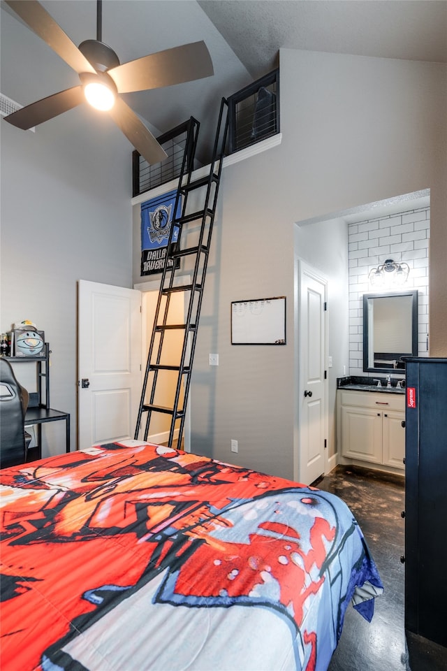 bedroom with ensuite bath, concrete flooring, and high vaulted ceiling