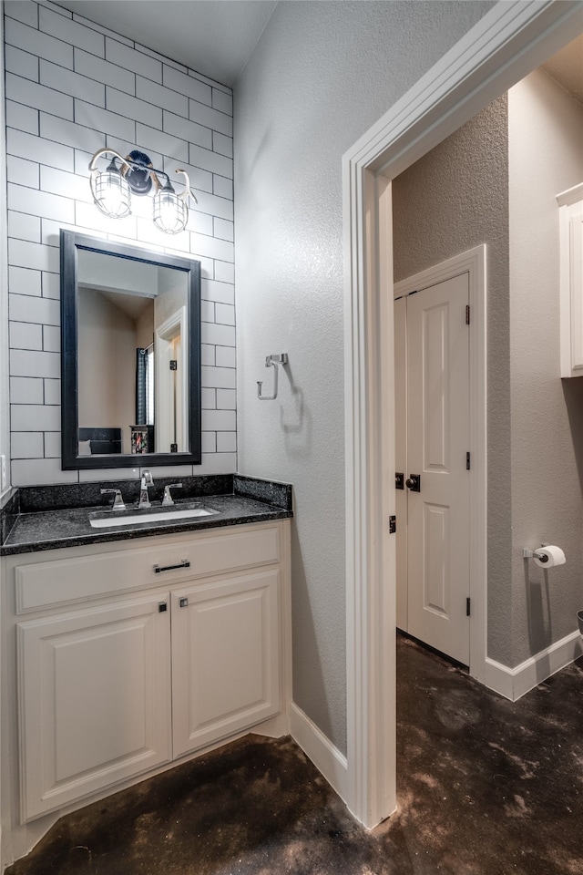 bathroom featuring vanity, concrete floors, baseboards, and a textured wall