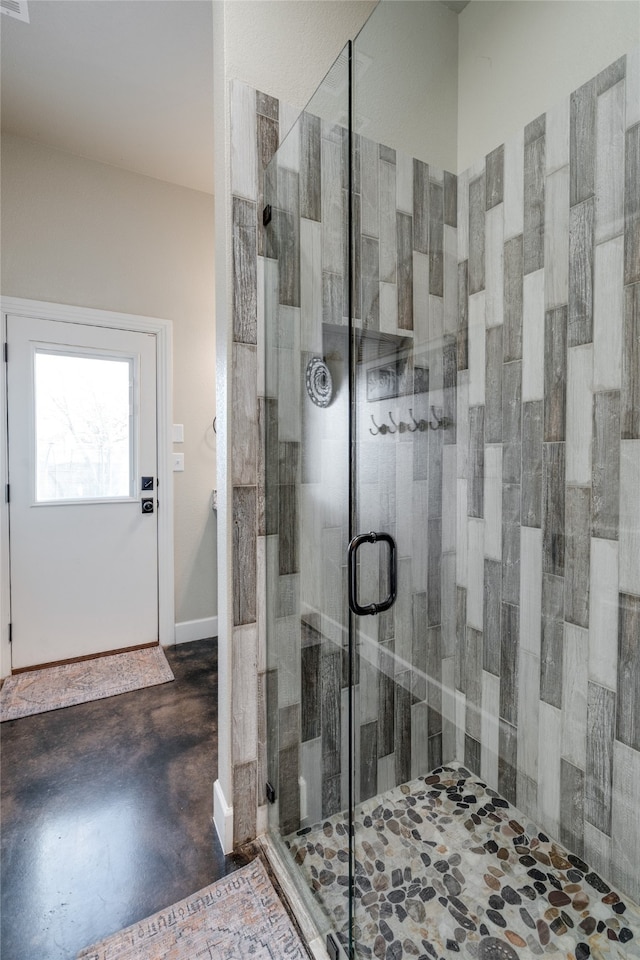 bathroom with a shower stall, concrete floors, and baseboards