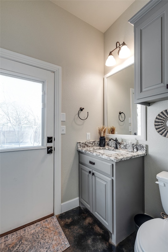 bathroom featuring a wealth of natural light, baseboards, toilet, and vanity