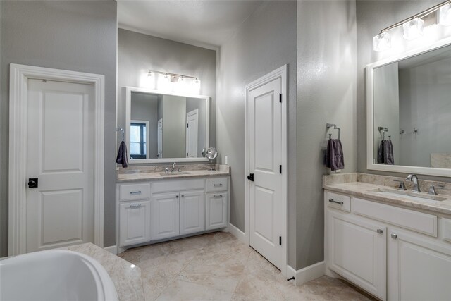 full bath with a sink, baseboards, two vanities, and a washtub