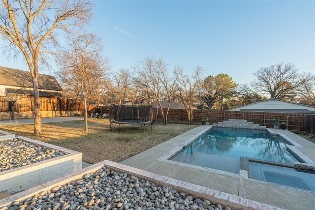 view of pool with a fenced backyard, a yard, and a trampoline