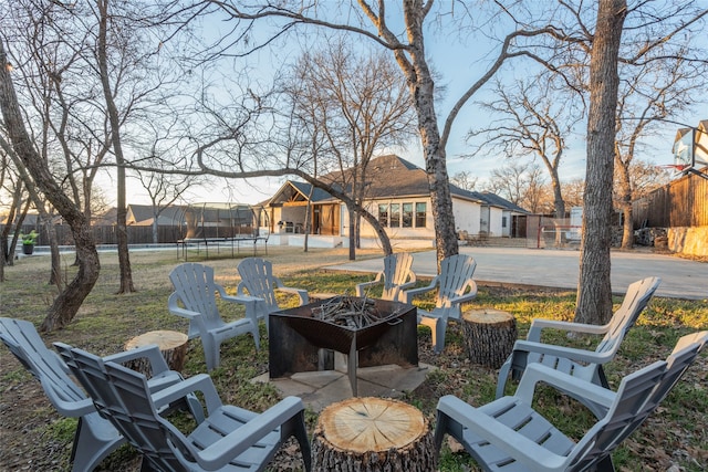 exterior space featuring a trampoline, fence, and an outdoor fire pit