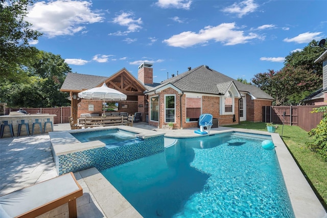 view of pool with a patio, a fenced backyard, a pool with connected hot tub, and outdoor dry bar