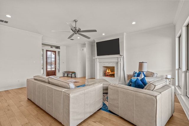 living area with light wood-type flooring, visible vents, ornamental molding, and a fireplace