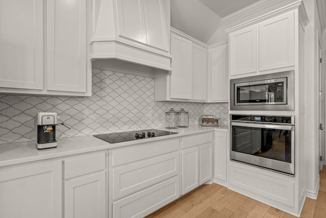 kitchen featuring premium range hood, stainless steel appliances, light wood-style floors, white cabinets, and light countertops