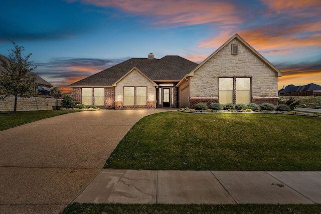 french provincial home with fence, driveway, a chimney, a lawn, and brick siding