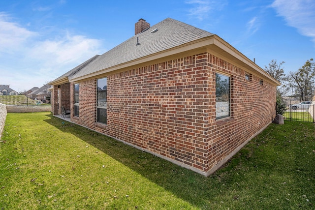 view of property exterior with a lawn, a chimney, brick siding, and fence