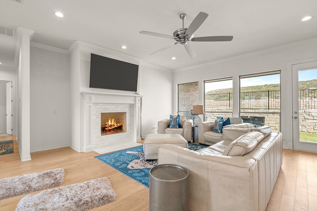 living area featuring light wood finished floors, recessed lighting, a fireplace, and crown molding