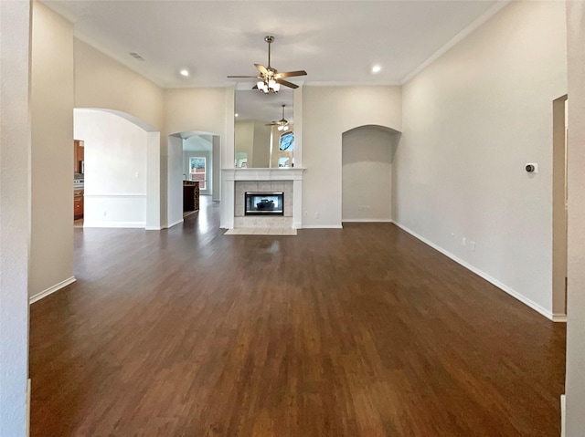 unfurnished living room featuring baseboards, a ceiling fan, dark wood finished floors, and a tiled fireplace