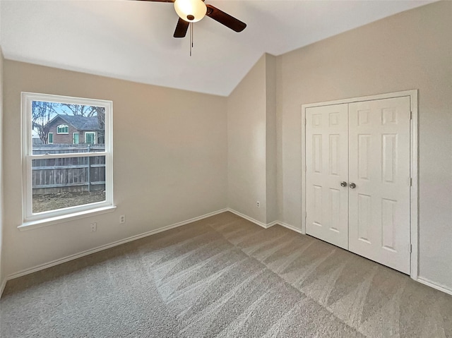 unfurnished bedroom featuring a ceiling fan, baseboards, vaulted ceiling, a closet, and carpet flooring